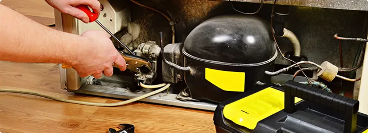 Refrigerator repair technician fixing the compressor and wiring in Nipton, CA