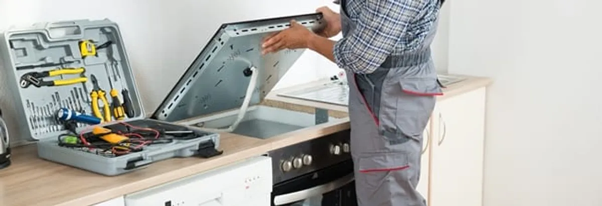 Cooktop repair technician lifting a built-in stovetop for service in Las Vegas, NV