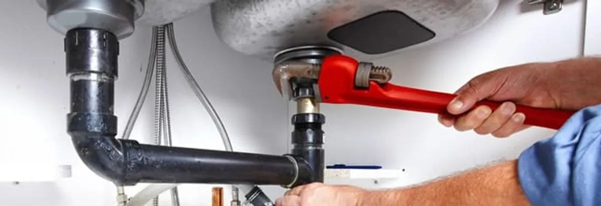 Garbage disposal repair technician tightening the sink drain and disposal connection in Las Vegas, NV