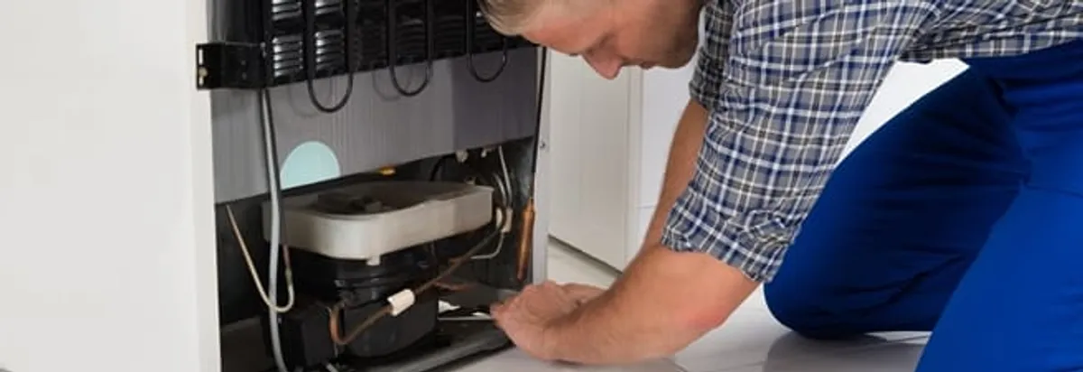 Refrigerator repair technician servicing the compressor and condenser area in Las Vegas, NV
